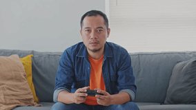 Asian Man Playing Video Game Using Joystick and Yawning Feel Sleepy  at Home. 