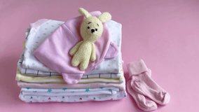 Stack of Baby bodysuits. Baby knitted toy of bunny next to a stack rompers for kids
