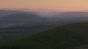 Sunrise over Odorheiu Secuiesc city in Transylvania. Aerial 4k video with Odorheiu Secuiesc and a beautiful forest in foreground. Travel to Romania.