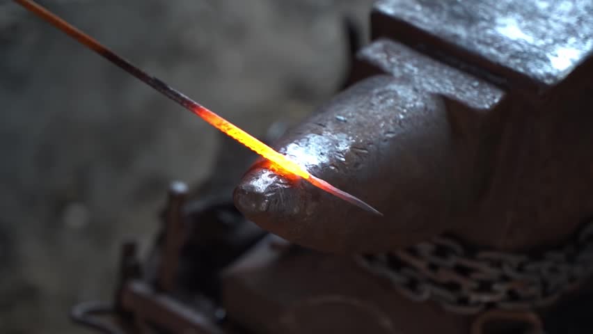 Blacksmith in a forge at work on an anvil. Hot metal forging