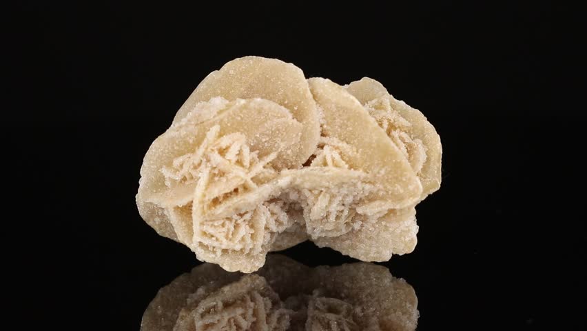 Polished mineral stone Desert rose rotates in a circle on a black background close up