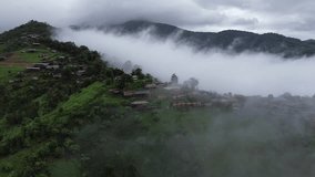 4k high-angle view rural village on the mountain covered with rainy season mist After heavy rain, the weather is cool and wet. Rich mountain forest Village in the mountains of Thailand
