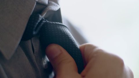 Close-up of hispanic man getting ready tying a necktie in the morning