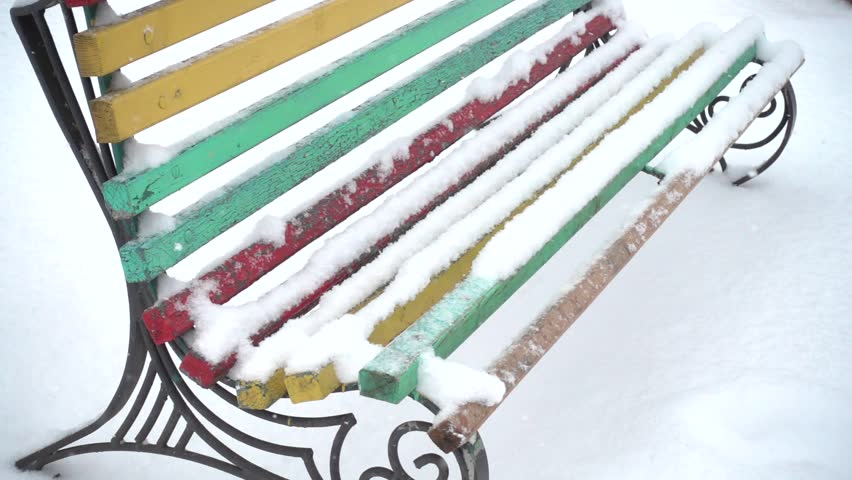 Bench in the square and the falling snow. Slow motion.
