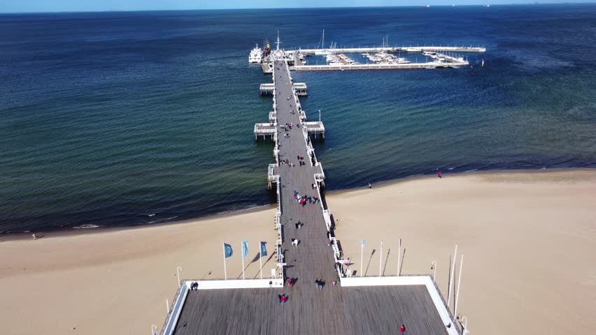 People Strolling On The Pleasure Long Wooden Pier Of Sopot On The Gdańsk Bay In Poland. Aerial Drone Shot