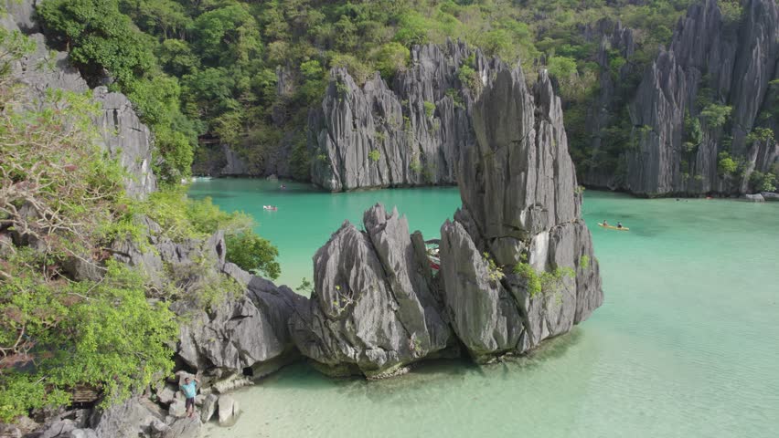Aerial view of the amazing Big Lagoon in El Nido, Palawan, Philippines. Shallow lagoon with blue water amid jagged Karst Rock cliffs and lush tropical jungle. Royalty-Free Stock Footage #3497235191