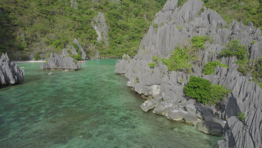 Aerial view of the amazing Big Lagoon in El Nido, Palawan, Philippines. Shallow lagoon with blue water amid jagged Karst Rock cliffs and lush tropical jungle. Royalty-Free Stock Footage #3497235395