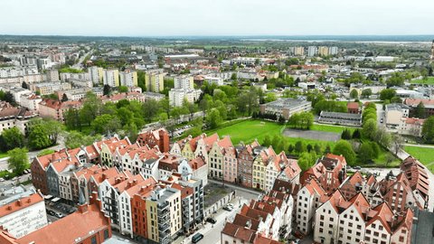 An aerial the majestic spire of a cathedral towering over the quaint and colorful townhouses of a vibrant city. Tapestry of architectural history and modern living in Elbląg. Stockvideó