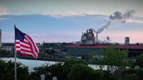 The American flag flies above a large manufacturing facility at dusk. - Powered by Shutterstock - Get 15% off with code: PIKWIZARD15