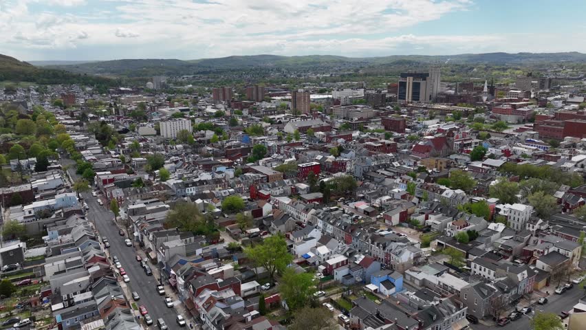 Wide aerial shot of an American city. Drone view flying towards downtown skyscrapers above row houses and neighborhoods.