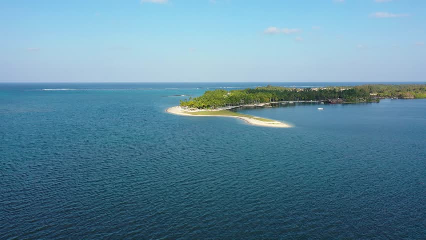 Drone overhead view of the beach of Constance Belle Mare Plage in Mauritius, with palm trees, umbrellas and a beautiful turquoise sea with transparent water. Luxury 5 star hotel in Mauritius.