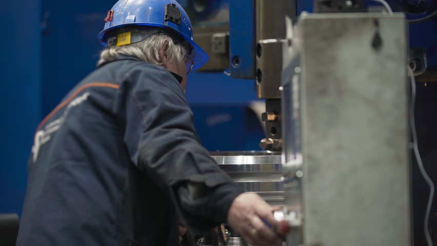 An engineer operating the modern CNC machine at the industrial facility. An engineer uses a control panel of the CNC machine. An engineer produced heavy industry items using a CNC machine. Royalty-Free Stock Footage #3497364473