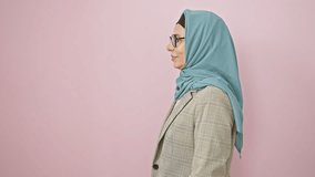 Confident middle age hispanic woman strikes an elegant side pose in hijab, serious yet natural smile lightens up her face against a stark pink backdrop - Powered by Shutterstock - Get 15% off with code: PIKWIZARD15