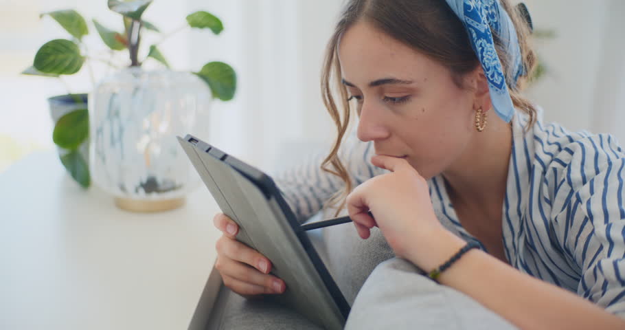 A focused portrait capturing a woman deeply immersed in online learning, utilizing her digital tablet to expand her knowledge and skills