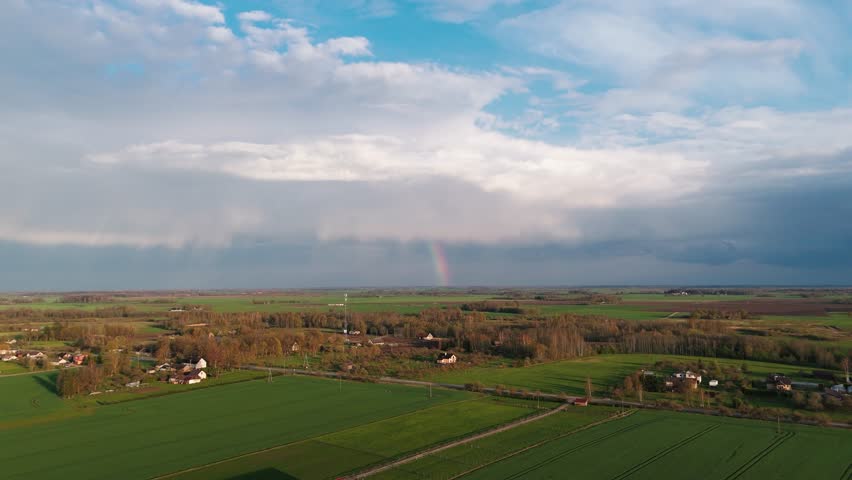 The Rainbow Over the Green Field After Storm With Rain, During Spring, Aerial View Under Heavy Clouds Before Thunderstorm. Agriculture Landscape Many Green Fields. Aerial 4k Shot