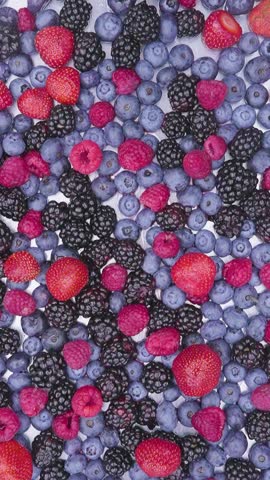 Mix of red blue and black berries dropping in epic slow motion 