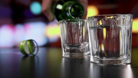 Hand pouring Korean soju into clear shot glasses with bokeh blurry bar background - Powered by Shutterstock - Get 15% off with code: PIKWIZARD15