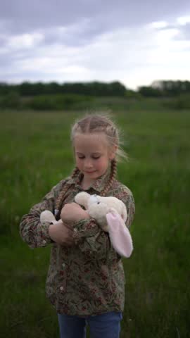 a little girl cradles her toy bunny as a baby in a field Royalty-Free Stock Footage #3497547359