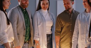 Group of happy creative smiling business people men and women standing in a row holding and connecting lightbulbs indoors. Innovative thinking and idea concept. 4k video. Slow motion video.
