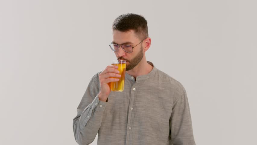 Young adult man, Caucasian brunette in glasses, drinks apple juice.