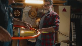 An elderly man in his 60s is having fun with his friends playing with a hula hoop in the garage at home - Powered by Shutterstock - Get 15% off with code: PIKWIZARD15