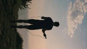 Man jumping rope outdoor at nature, silhouette vertical video - Powered by Shutterstock - Get 15% off with code: PIKWIZARD15
