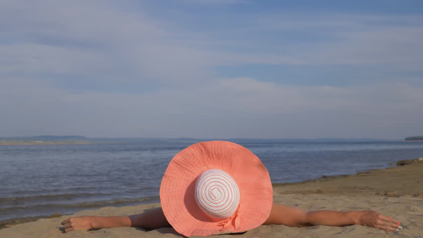 Beautiful woman is lying on the beach and doing warm-up legs. Her legs are up. She