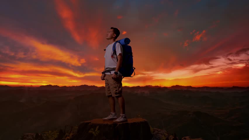 Full Body Side View Of Asian Male Hiker With Mountaineering Backpack Screaming Goal Celebrating The Success While Standing On Top Mountain During Sunset Time