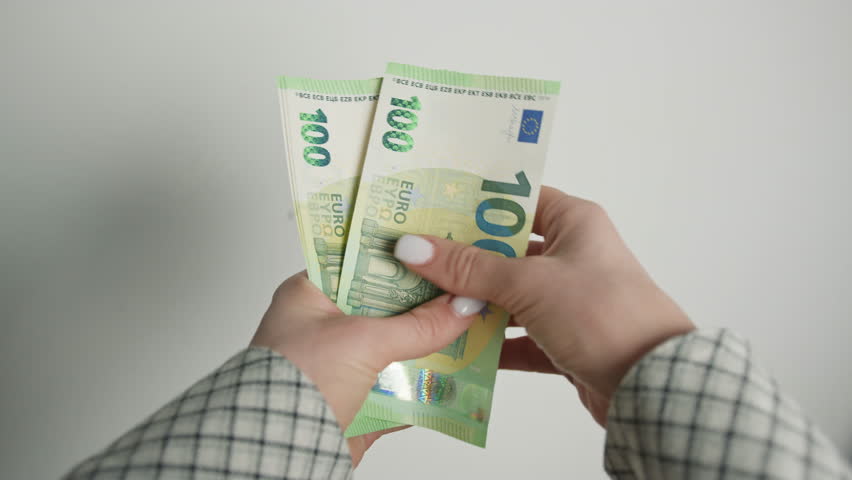 Close-Up View of a Businesswoman in a Checkered Jacket Counting Fresh 100 Euro Bills, Highlighting Currency Exchange and Financial Transactions