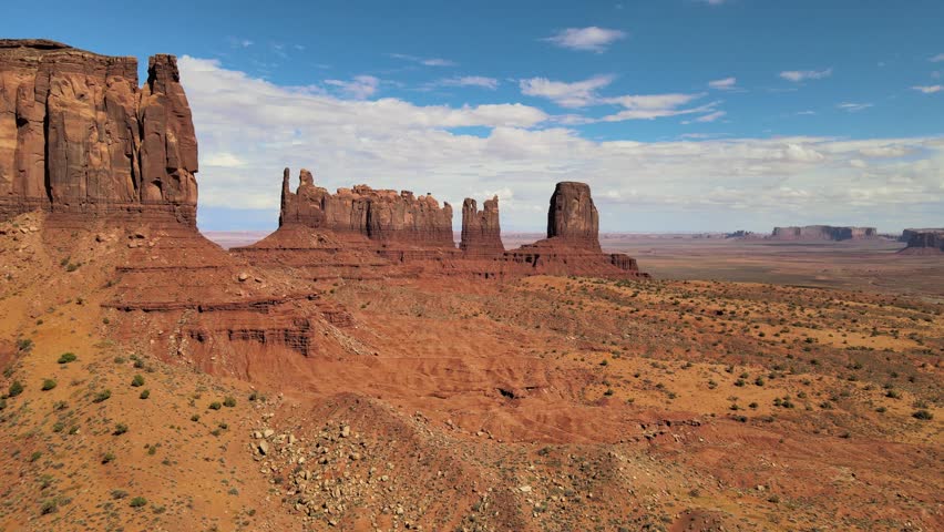 Explore the rugged beauty of a desert landscape in Monument Valley, Utah. Witness towering mountains, rocky terrain, and barren valleys from a birds eye perspective.