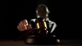 Female sitting at the desk with wooden hammer, dark room bright spotlight. Woman judge silhouette in the court room, hitting wooden gavel, focus on the mallet, close up. - Powered by Shutterstock - Get 15% off with code: PIKWIZARD15