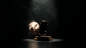 Man at the desk with wooden hammer, dark room bright spotlight and smoke. Man judge in the court room, hand hitting wooden gavel, close up shot of mallet. - Powered by Shutterstock - Get 15% off with code: PIKWIZARD15