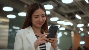 Young happy business asian woman working and touching on screen of cell phone for communication, female with casual outfit checking email and playing media app, people enjoy lifestyle in city.