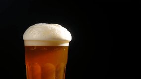 Foamy beer in a glass close-up, overflowing with foam. Alcoholic golden beer drink in a mug. Fresh light ale on a black background. - Powered by Shutterstock - Get 15% off with code: PIKWIZARD15