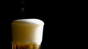 Foamy beer in a glass close-up, overflowing with foam. Alcoholic golden beer drink in a mug. Fresh light ale on a black background. - Powered by Shutterstock - Get 15% off with code: PIKWIZARD15