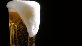Foamy beer in a glass close-up, overflowing with foam. Alcoholic golden beer drink in a mug. Fresh light ale on a black background. - Powered by Shutterstock - Get 15% off with code: PIKWIZARD15