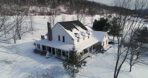 A slow dollying down establishing shot of a typical snow-covered farmhouse in rural Pennsylvania in the winter.  	