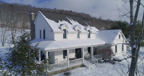 A slow aerial reverse establishing shot of a typical snow-covered Pennsylvania rural farmhouse in Winter.	 	