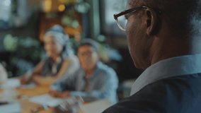 African American professor talking in front of group of diverse adult students sitting around table in classroom and listening attentively during English class in school for immigrants. Rack focus - Powered by Shutterstock - Get 15% off with code: PIKWIZARD15