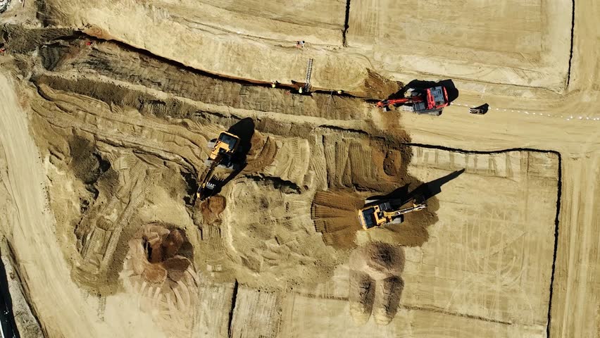 Caterpillar backhoes digging dirt, earth for pipes at new Toll Brothers Tesoro Highlands homes construction site. Industrial equipment. Drop down