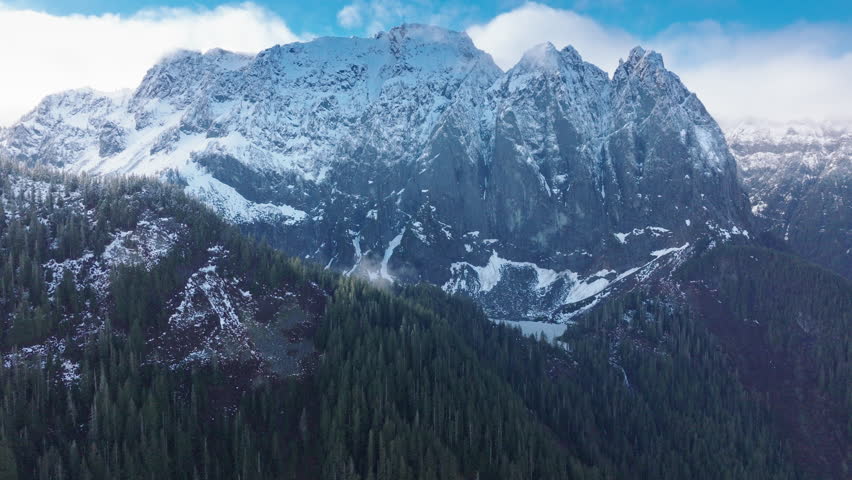 Aerial perspective of a vibrant green forest and a striking mountain under overcast skies in Washington. 4K footage. 