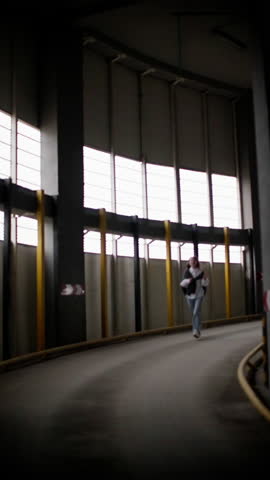 Motion blur of young woman running in an industrial parking garage, dynamic urban scene