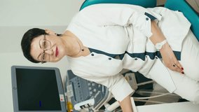 Vertical shot of a woman doctor of ultrasound diagnostics near the machine. Diagnosis in the clinic is a step towards a healthy life. High quality 4k footage