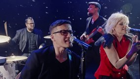 Pop singers singing and dancing on stage. Drummer and guitarist playing instruments in background. Musicians performing rock music on snowy event.  - Powered by Shutterstock - Get 15% off with code: PIKWIZARD15