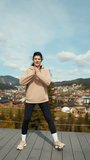 Young woman does morning exercises on the terrace of a hotel overlooking the snow-capped mountains. The concept of a healthy lifestyle. Vertical video
