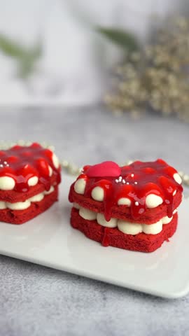 Beautiful red heart-shaped cake topped with strawberry jam on a gray background. Vertical video.