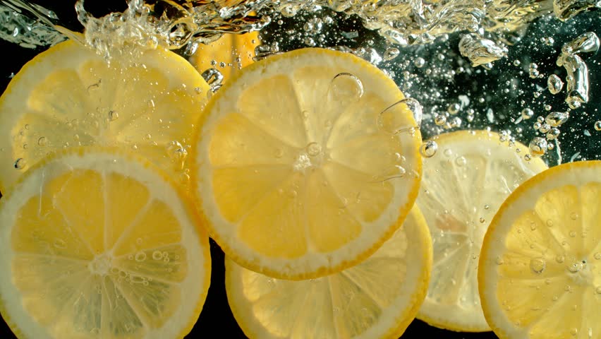 Super Slow Motion Shot of Fresh Lemon Slices Falling and Flowing in Water on Black at 1000 fps.