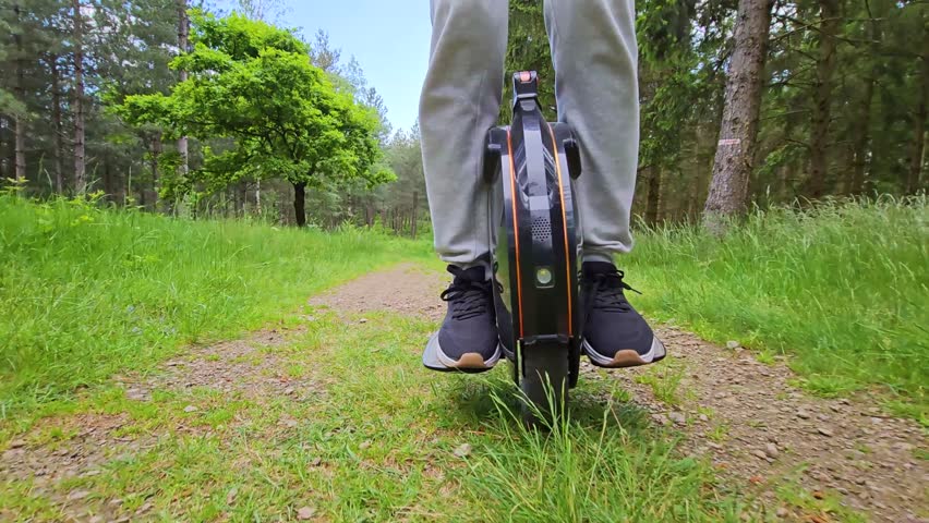 Close up of a monowheel being ridden along a forest track or path; close up, front view of man riding and balancing on electric unicycle, outside in nature; personal modern battery powered transport
 Royalty-Free Stock Footage #3498404015