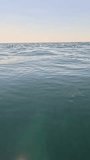 Sea water surface. Low angle view from kayak, camera flies over clear sea water. Nobody. Holiday recreation concept. Abstract nautical summer ocean nature. Slow motion. Close up. Vertical video