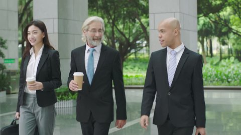 multiethnic corporate executives with coffee and computer bag arriving at modern building. 